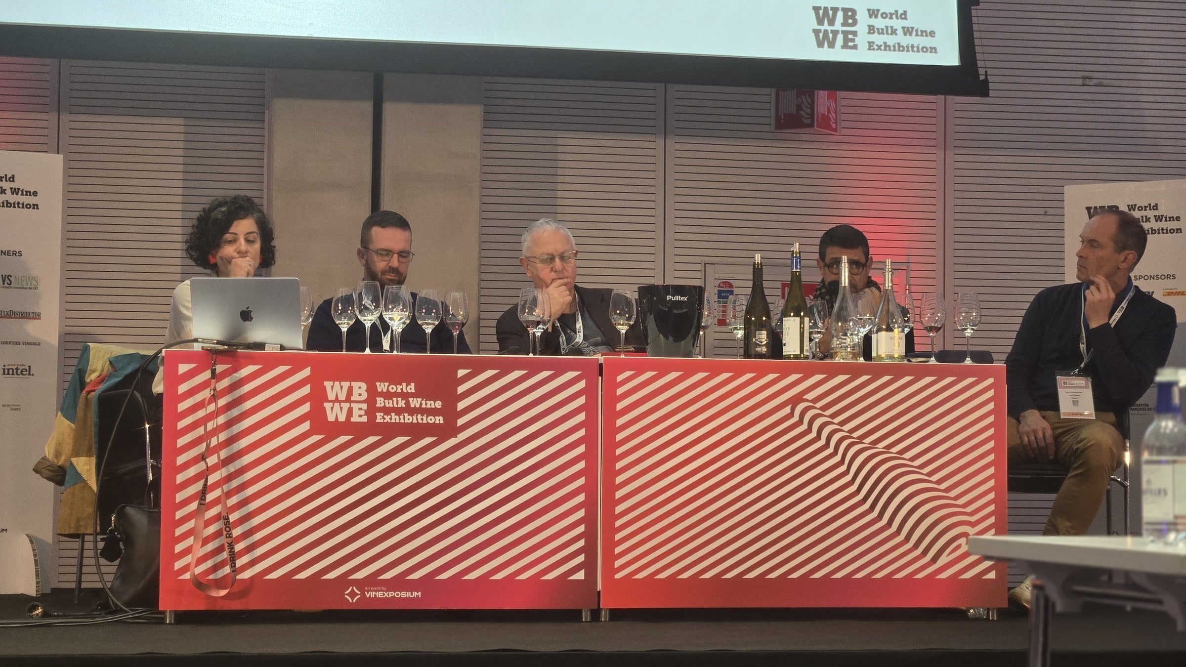 The no and low alcohol masterclass panel seated at the red WBWE-branded table with glasses and bottles in front, at the World Bulk Wine Exhibition in RAI Amsterdam, November 2025.
