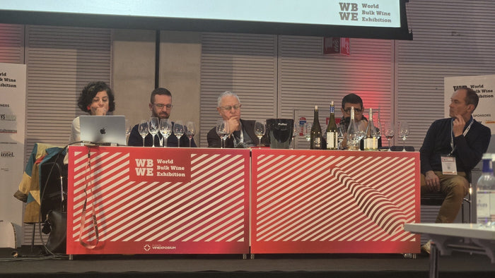 The no and low alcohol masterclass panel seated at the red WBWE-branded table with glasses and bottles in front, at the World Bulk Wine Exhibition in RAI Amsterdam, November 2025.