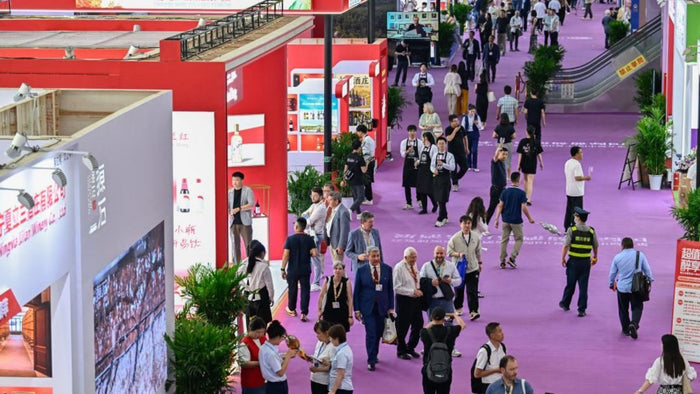 Busy trade floor of the 2025 Expo of Wine at the Yinchuan International Convention Centre in Ningxia, China, with visitors walking between red exhibition booths.