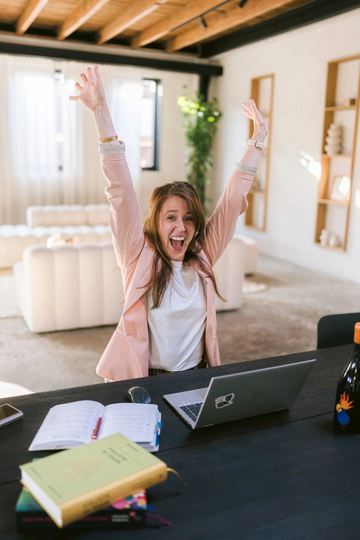 Margot van Lieshout cheering with raised arms behind her laptop